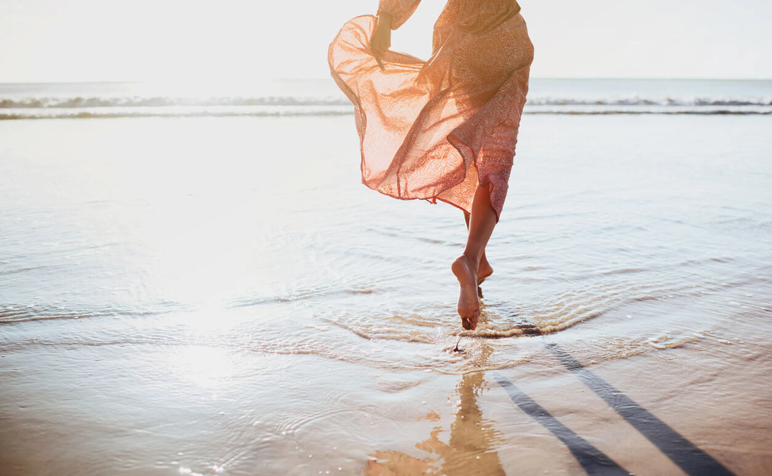 Frau im Strandkleid am Strand im Meer