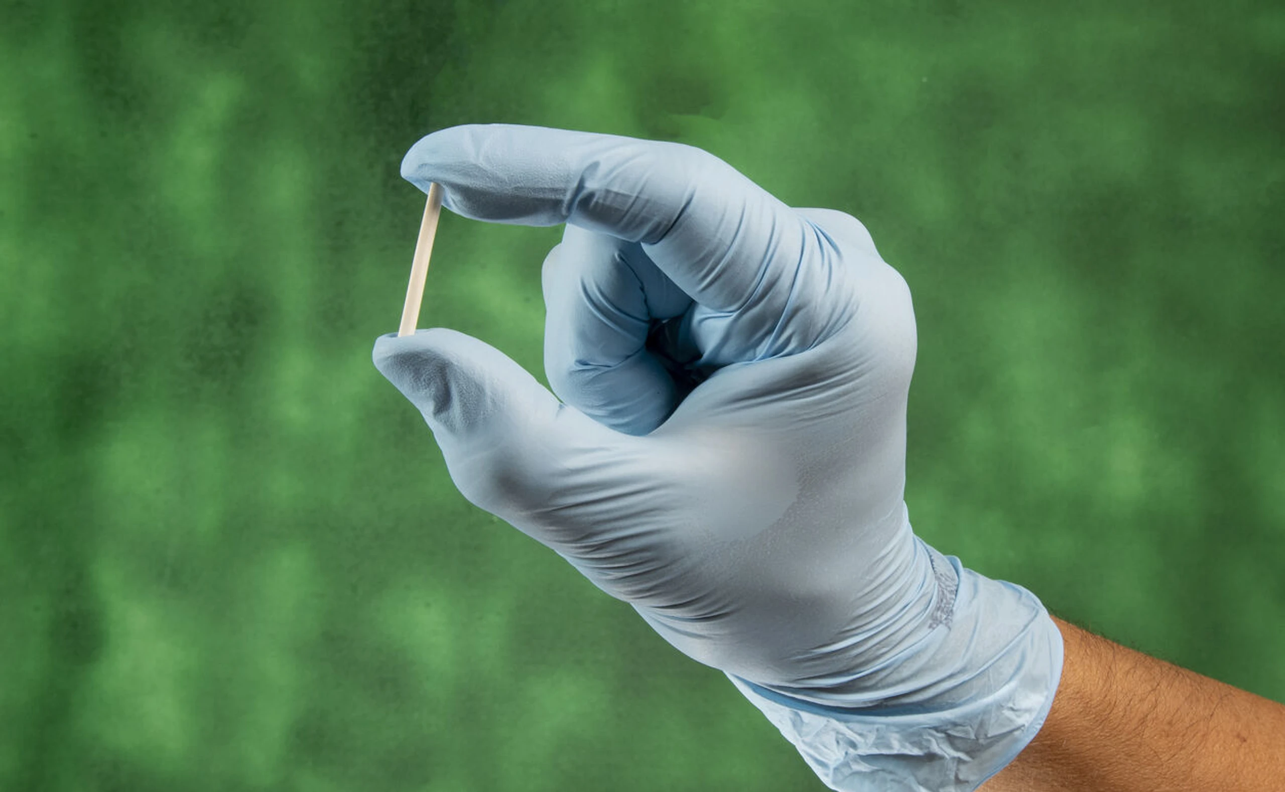 Eine Hand mit Handschuh hält ein Hormonstäbchen