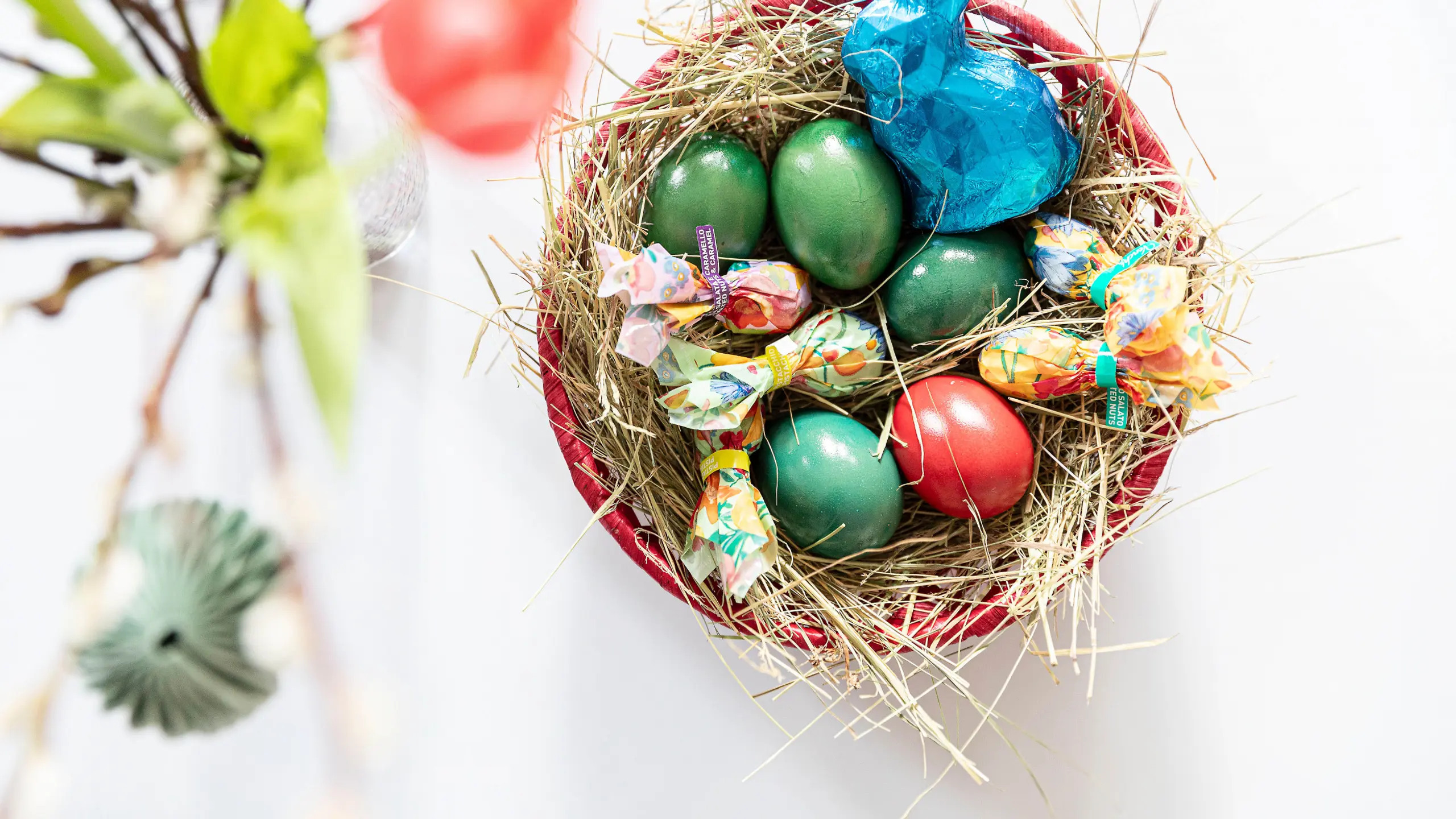Osternest, das mit bunten Ostereiern und Süßigkeiten gefüllt ist