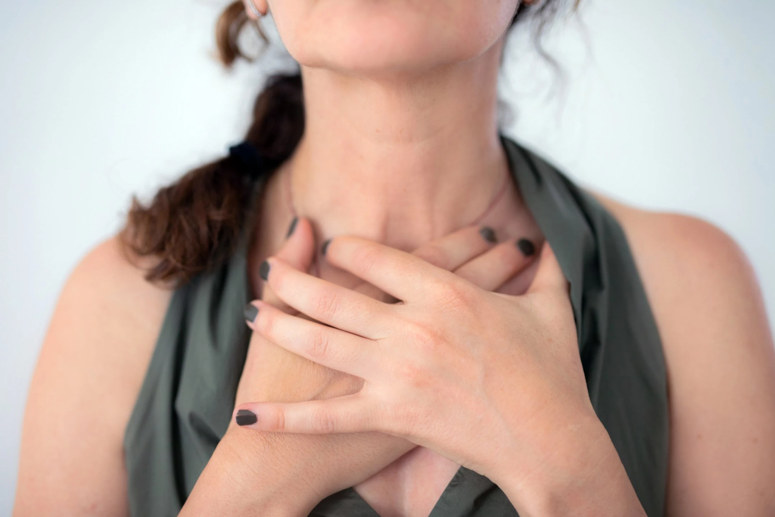 Frau, die sich mit beiden Händen an den Hals greift