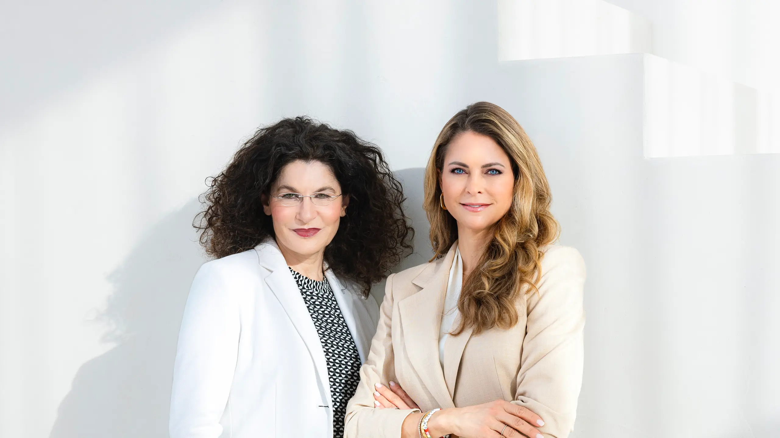 Tina Müller (links) gemeinsam mit Prinzessin Madeleine (rechts) vor einer weißen Wand