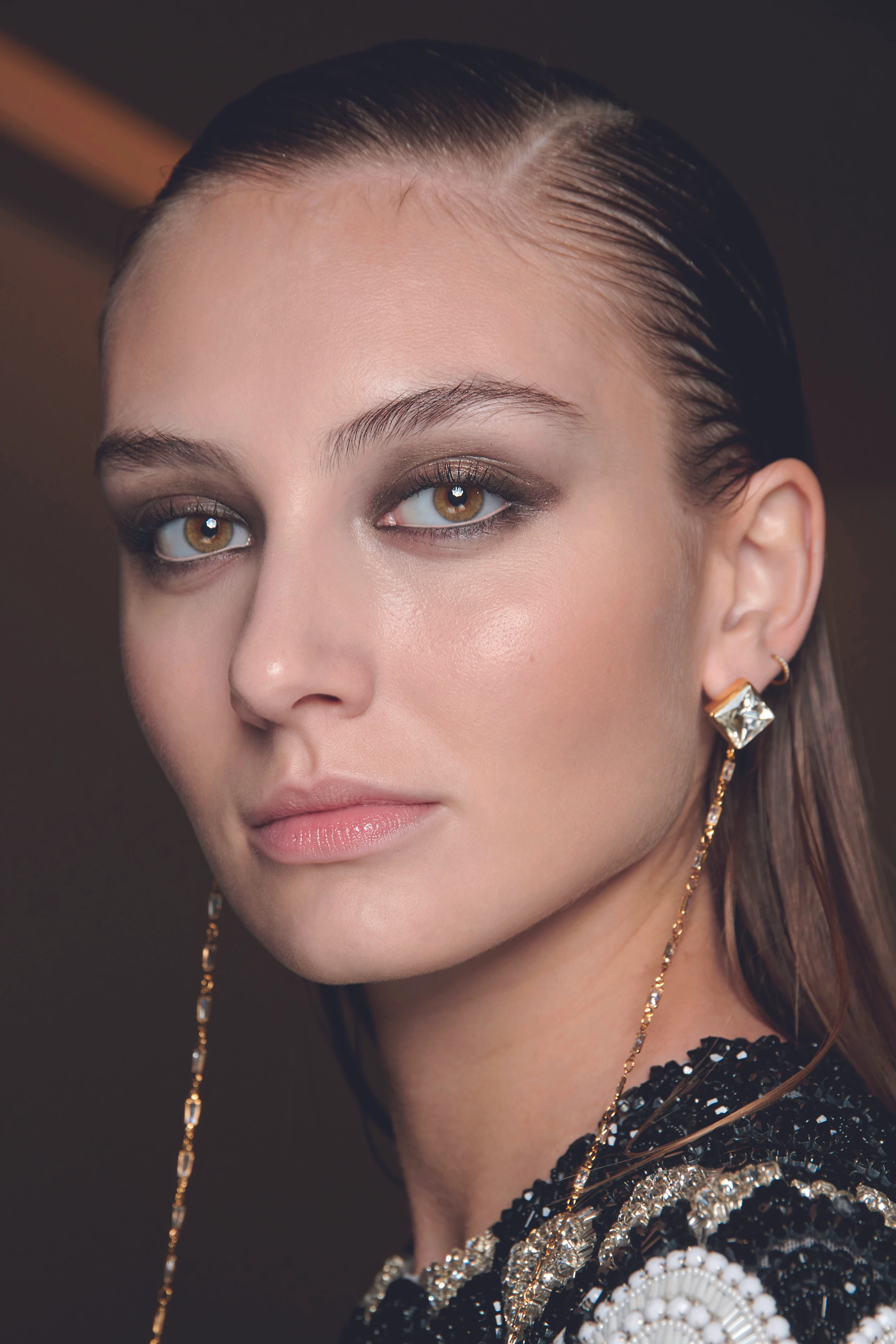 Model BTS mit brauen schimmernden Smokey-Eyes und zurückgegelte Haare