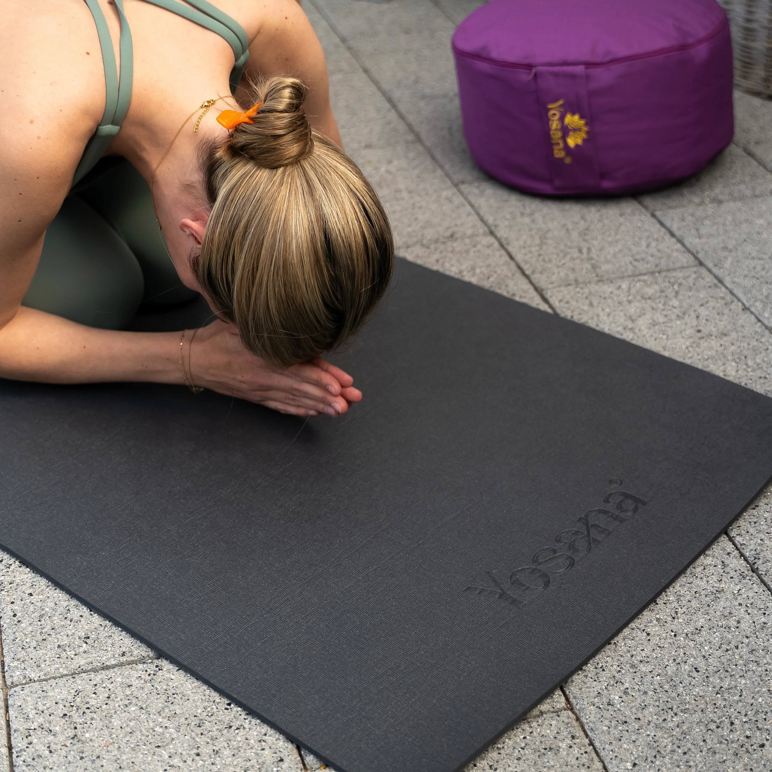 Eine Frau kniet auf einer Yogamatte und hat ihren Kopf bis zur Matte gebeugt