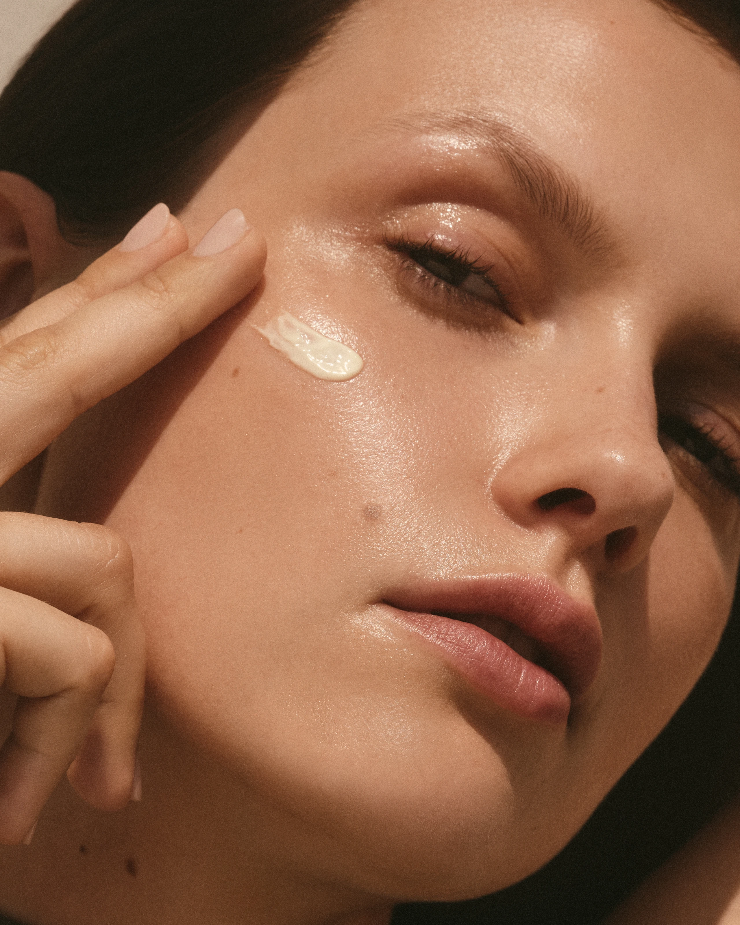 Nahaufnahme von einem Gesicht einer Frau, sie hat Creme auf der Wange