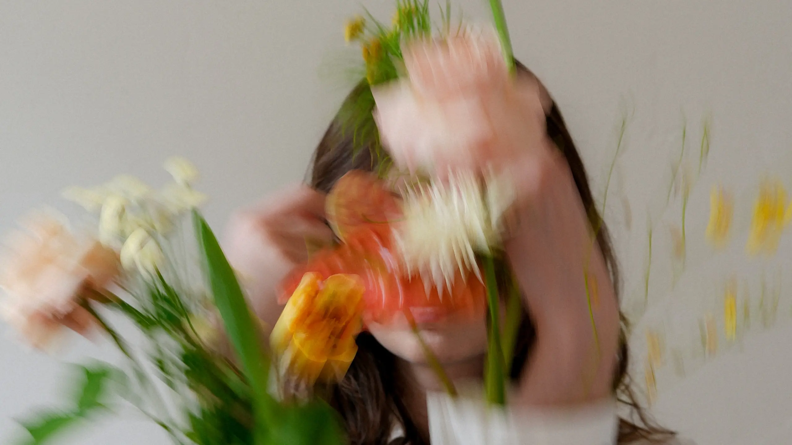 eine Frau in weißem Hemd, sie hat Blumen in den Ärmeln, das Bild ist unscharf