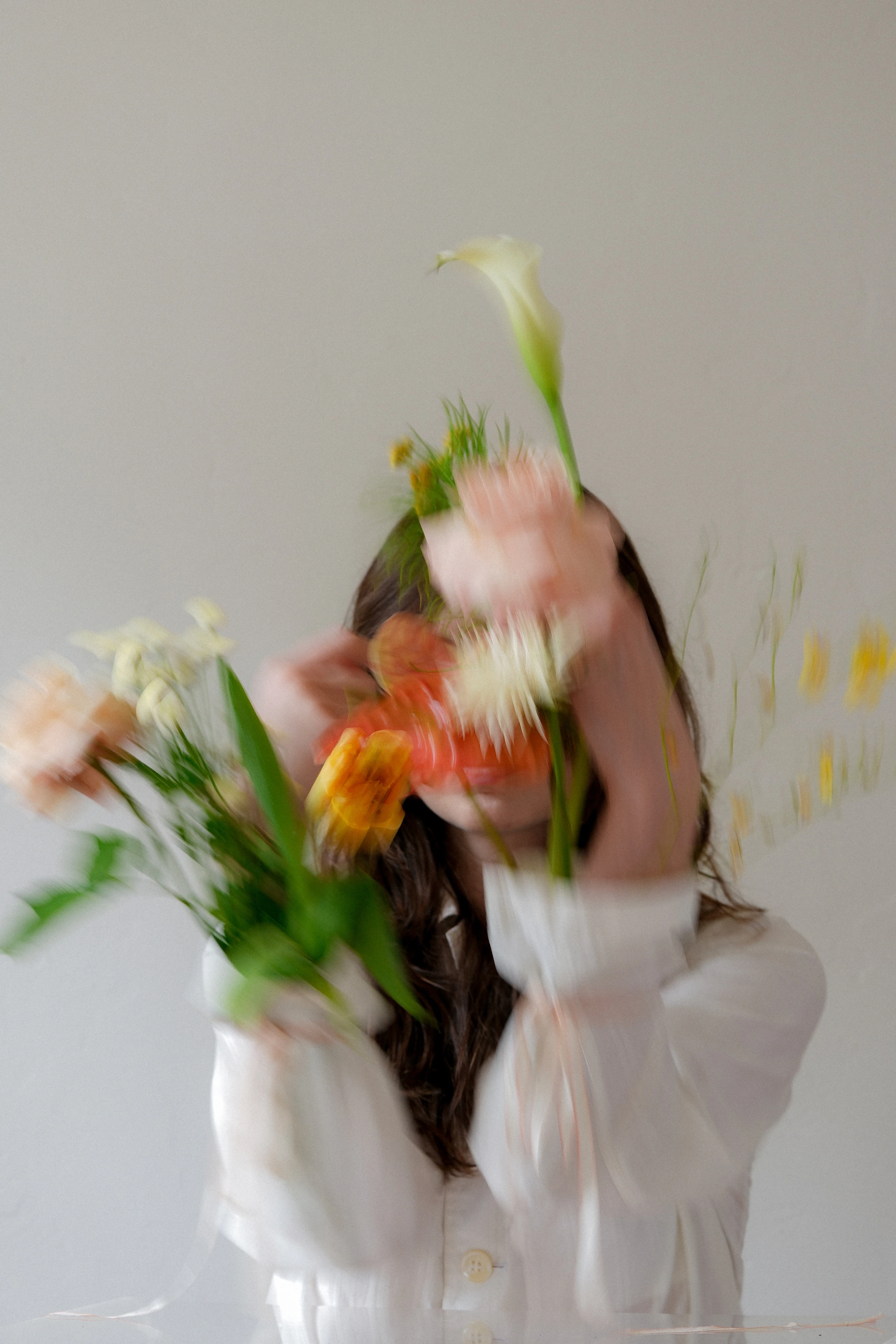 eine Frau in weißem Hemd, sie hat Blumen in den Ärmeln, das Bild ist unscharf