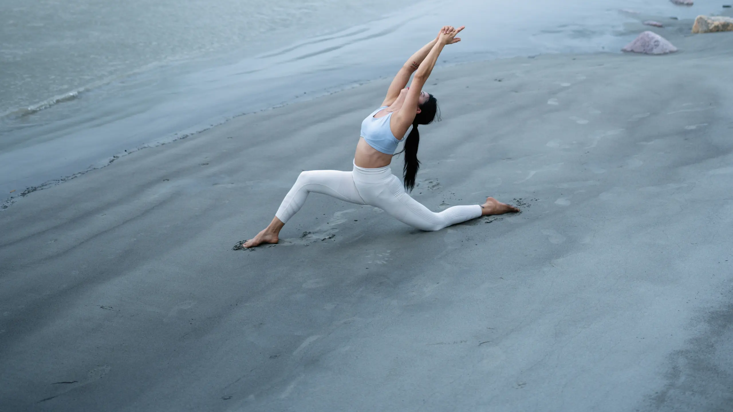 Eine Frau macht Yoga am Strand, es etwas nebelig oder wolkig