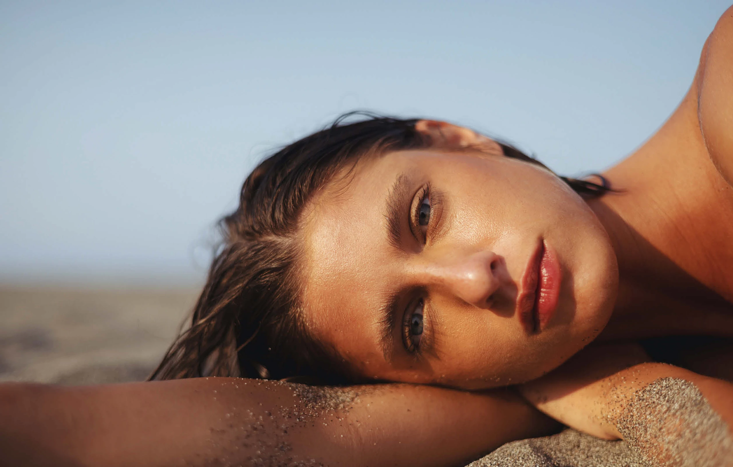 Frau liegt seitwärts im Sand
