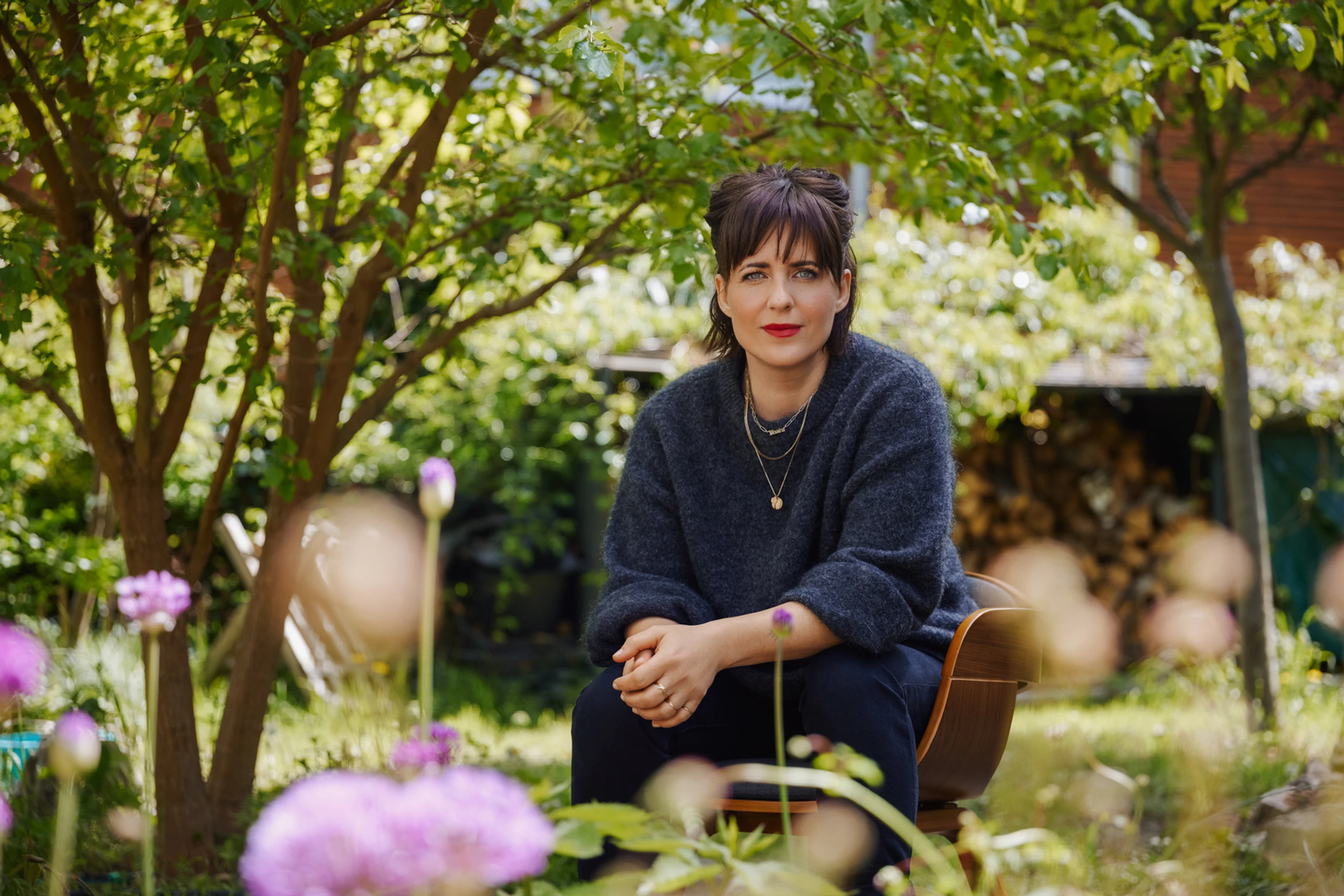 Sarah Kuttner sitzt in einem Garten